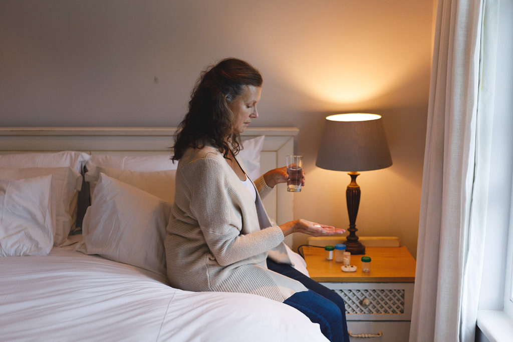 woman in bed taking a pill